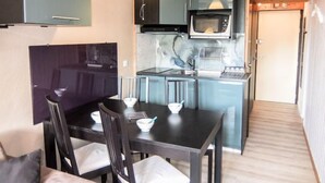 Una cocina compacta con una mesa de comedor y sillas, un microondas y un horno pequeño.