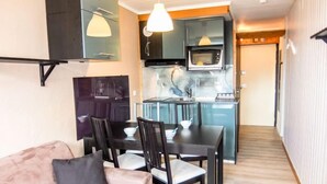 Un espacio habitable compacto con kitchenette, comedor y sofá.