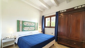 A bedroom with a bed, a nightstand, a window with curtains, and a wooden wardrobe. - La Rosa sul Mare by Interhome (Siracusa)