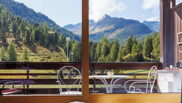 Ein Balkon mit Tisch und Stühlen mit Blick auf eine Berglandschaft.