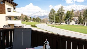 Ein Balkon mit einem für Tee gedeckten Tisch, mit Blick auf eine Straße und ein Gebirge.