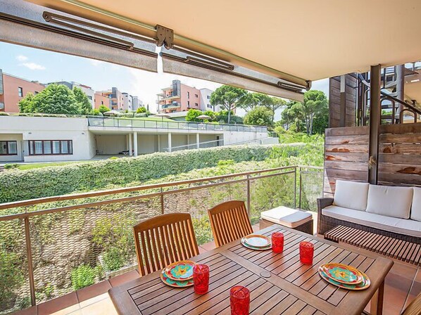 A balcony with a table set for two, chairs, and a sofa.