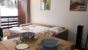 A hotel room with a bed, a dining table set with plates, glasses, and cutlery, and a painting on the wall. - Rosablanche D12 by Interhome (Siviez-Nendaz)