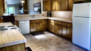Een keuken met houten kastjes, een witte koelkast, een fornuis en een vaatwasser.