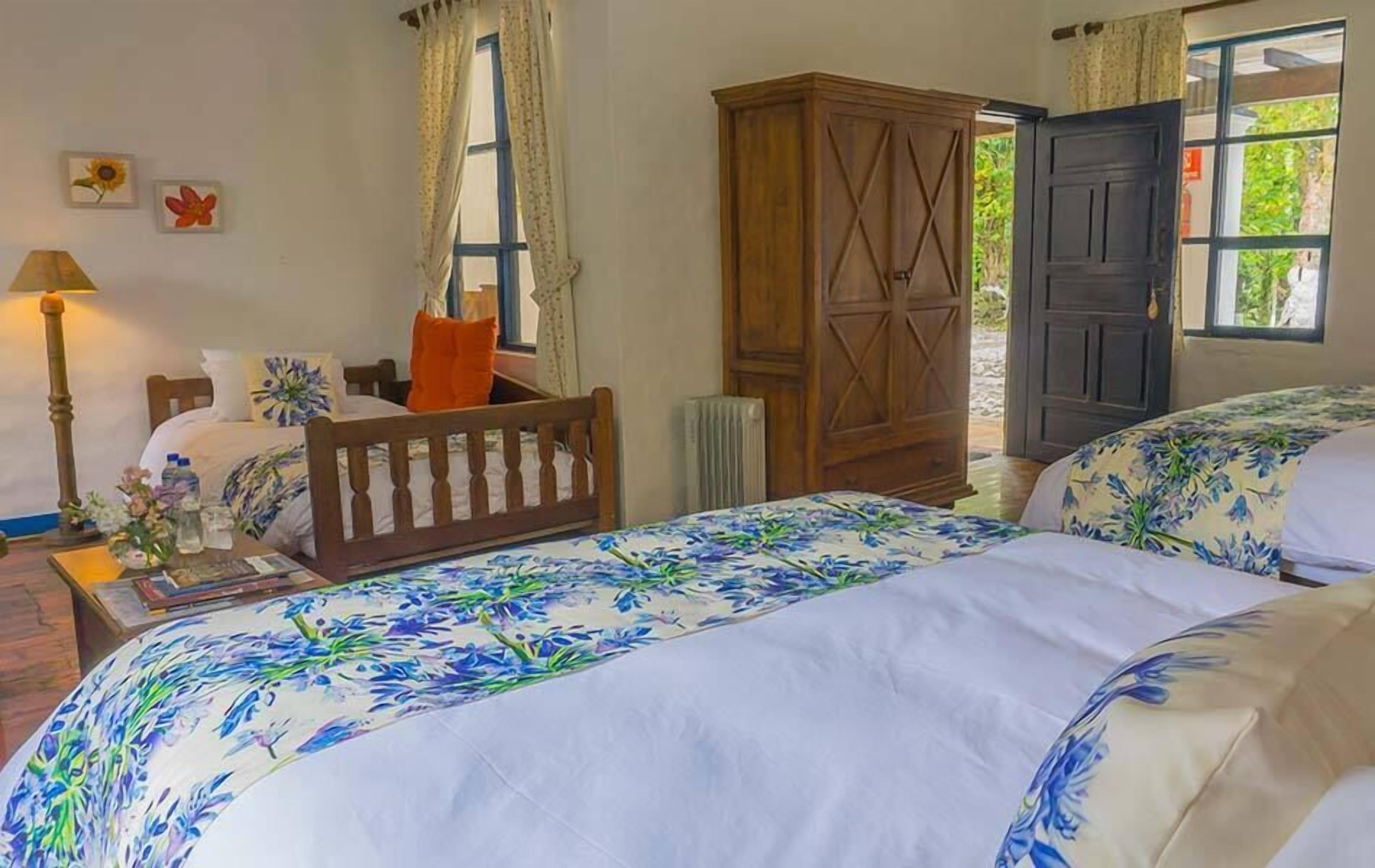 Ein Schlafzimmer mit zwei Betten, einem Holzschrank, einem Heizkörper und einem Fenster mit Vorhängen.