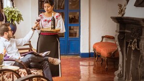 A traditional interior with a person serving wine, a fireplace, and a rustic setting. - Hosteria Hacienda Pinsaqui (San Juan de Ilumán)