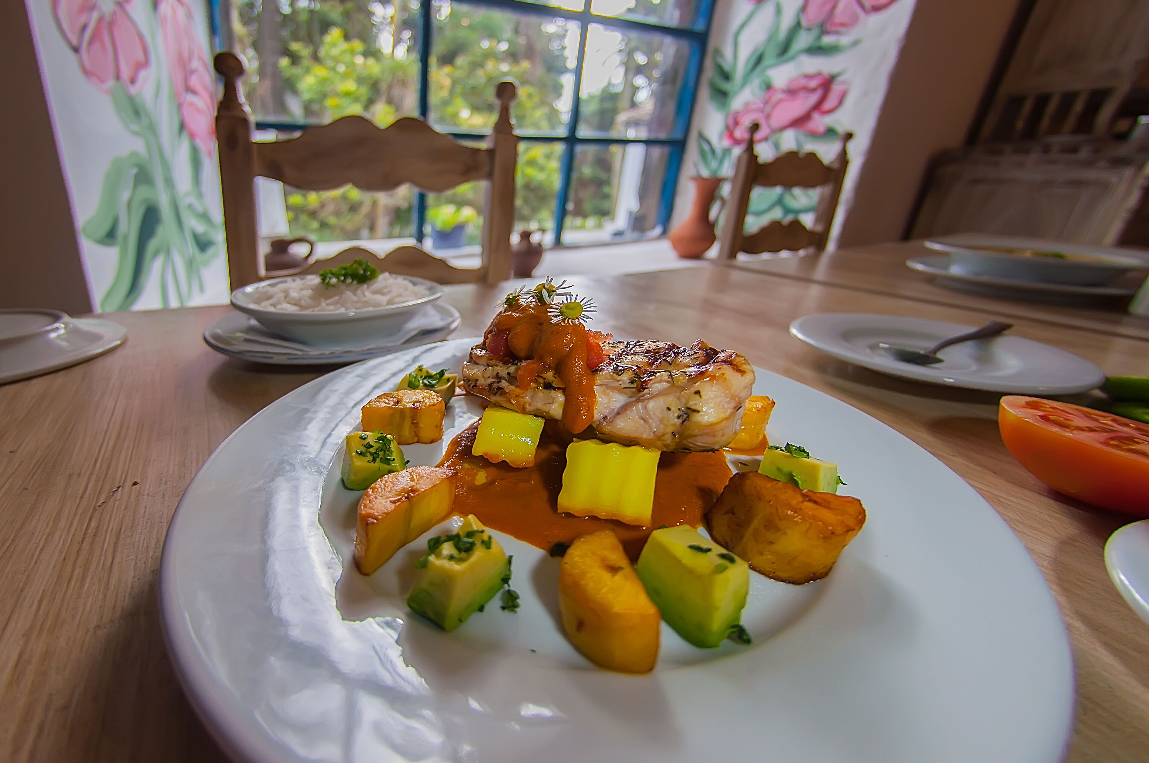 Une table à manger avec une assiette de nourriture, comprenant un morceau de viande, des pommes de terre et des légumes.