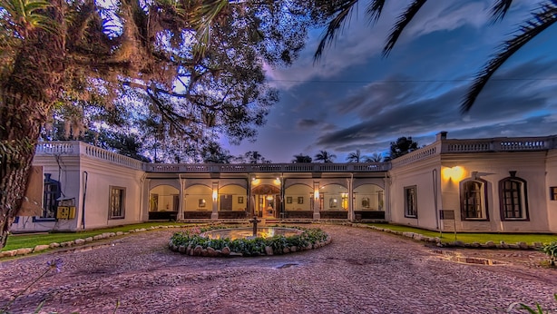 A courtyard with a central fountain, surrounded by a cobblestone path and lush greenery. - Hosteria Hacienda Pinsaqui (San Juan de Ilumán)