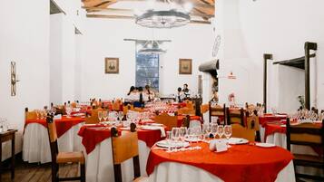 Un restaurante con varias mesas redondas cubiertas con manteles rojos y sillas blancas.