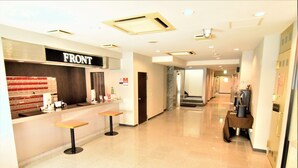 A hotel reception area with a 'FRONT' sign, a counter, and two bar stools. - Hotel New White House (Rumoi)