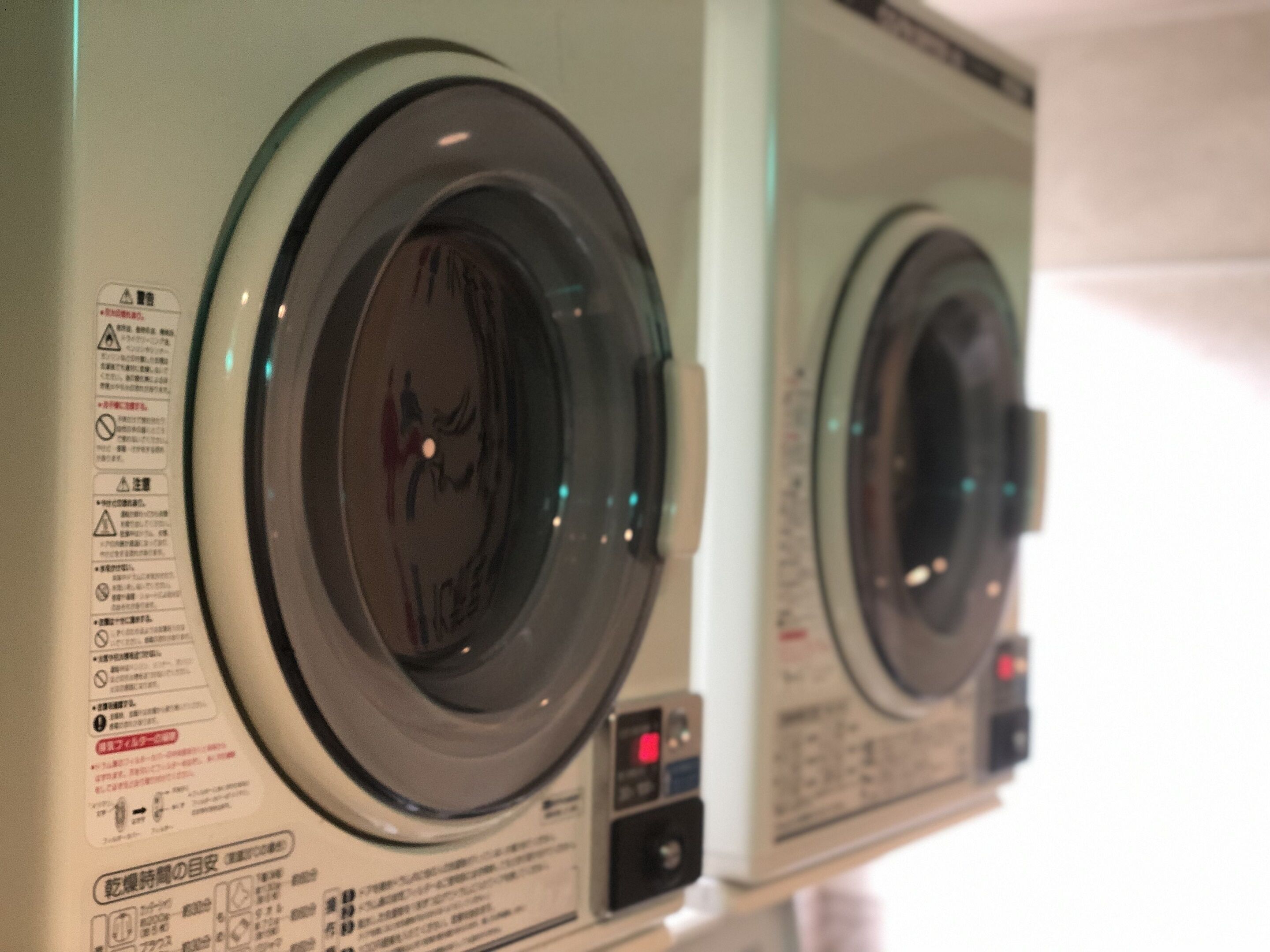 A row of front-loading washing machines with safety instructions and operational controls.