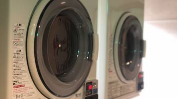 A row of front-loading washing machines with safety instructions and operational controls.