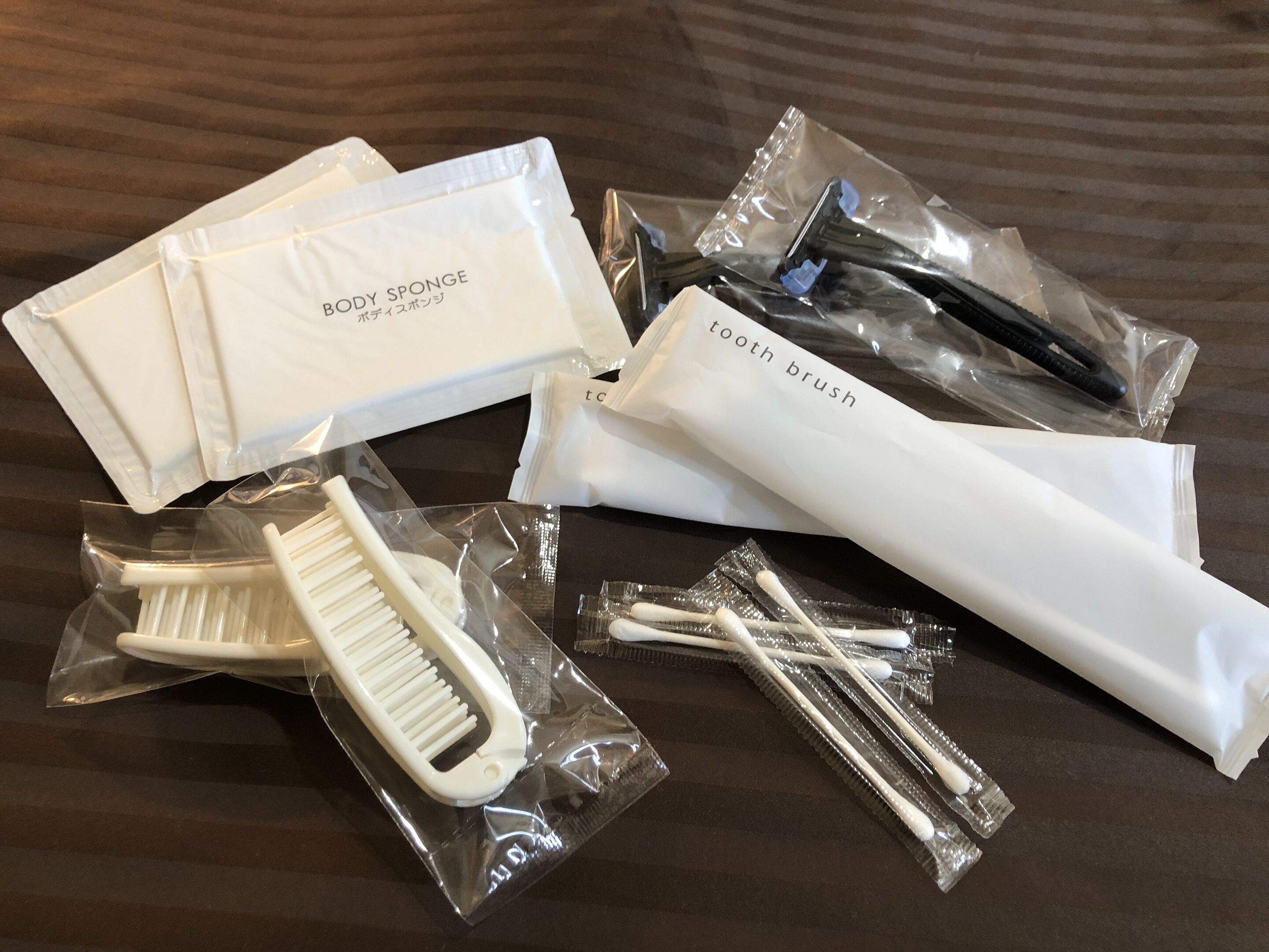 Een verzameling persoonlijke verzorgingsproducten, zoals een badspons, tandenborstel en wattenstaafjes, verpakt in doorzichtig plastic.