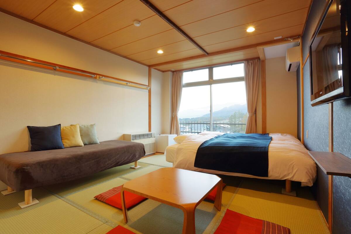 Una habitación de hotel con una cama, un sofá, una mesita y un televisor.