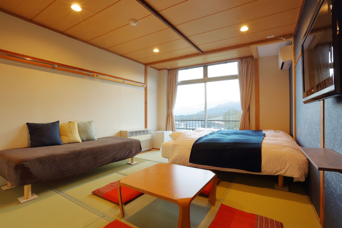 A hotel room with a bed, a sofa, a small table, and a TV.