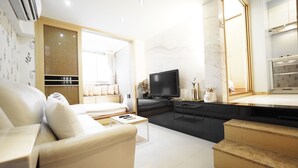 A modern living room with a sofa, a coffee table, a TV, and a kitchen area with a countertop and cabinets. - 5MIN to ATT 4 FUN (Taipei)