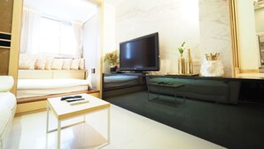 A modern living room with a sofa, a coffee table, a flat-screen TV, and decorative items. - 5MIN to ATT 4 FUN (Taipei)
