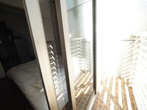 A room with a bed, a sliding glass door leading to a balcony with a brick floor and white railing. - 5MIN to ATT 4 FUN (Taipei)