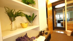 A hotel reception area with a reception desk, a plant on the shelf, a yellow bowl, and a wooden bench with a towel on it. - 5MIN to ATT 4 FUN (Taipei)