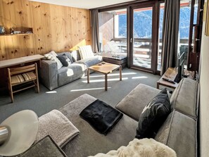Un soggiorno moderno con un divano, un tavolino e una parete decorativa in legno.