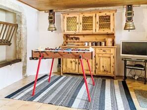 Une pièce chaleureuse avec un meuble en bois, un baby-foot et un téléviseur.