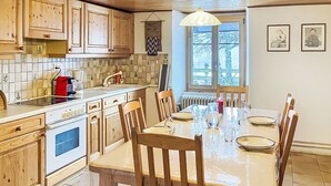 A kitchen with wooden cabinets, a stove, and a dining table set for six.