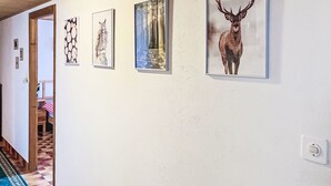 A hallway with four framed pictures on the wall, a wooden door, and a patterned carpet.