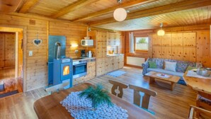A cozy wooden cabin interior with a kitchen, dining area, and seating space.