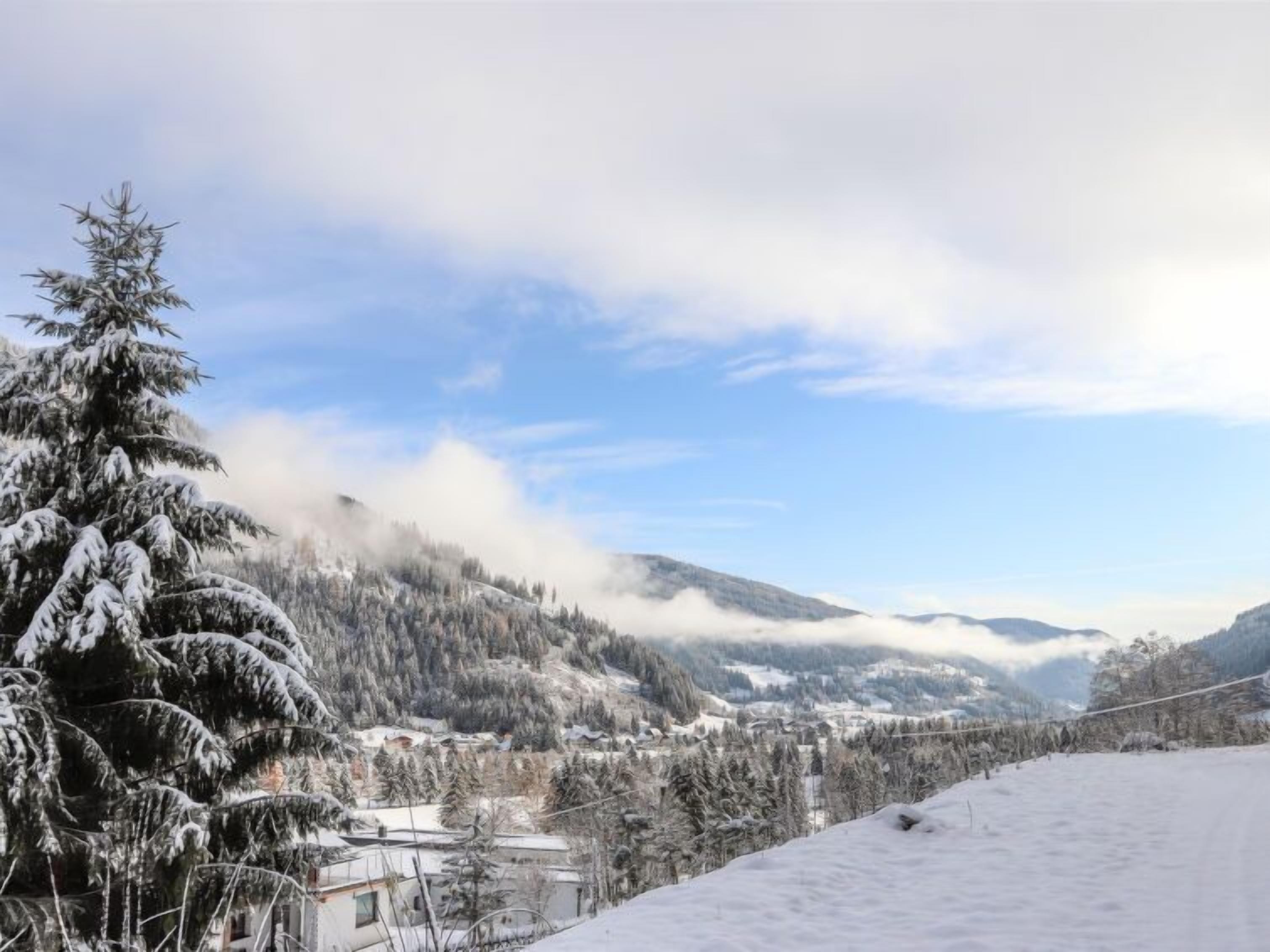 A snowy landscape with a mountain in the background and a clear sky.