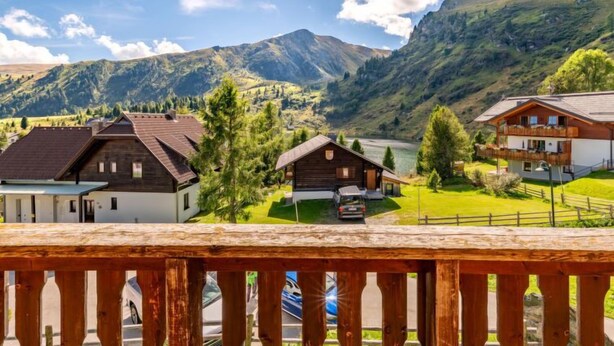 A mountain village with traditional wooden houses, a lake, and a clear sky.