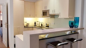 Une cuisine moderne dotée d’un îlot central, de tabourets de bar et d’un four à micro-ondes.