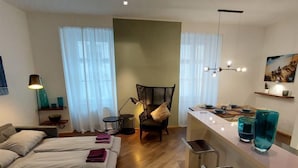 Une chambre d’hôtel moderne, équipée d’un lit, d’un bureau et d’une chaise. On y trouve une fenêtre avec des rideaux, une lampe et un tableau accroché au mur.