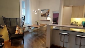 Une cuisine moderne dotée d’un îlot central, de tabourets de bar et d’un coin repas avec une chaise et une table.