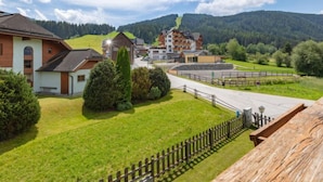 A hotel with a mountain view, a parking area, and a wooden fence.