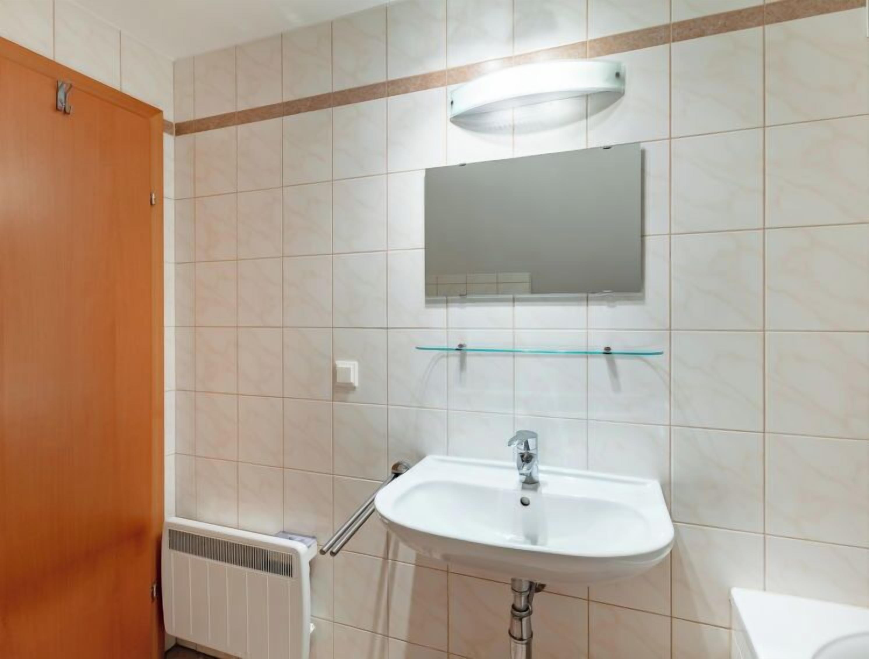 A bathroom with a white sink, a mirror above it, and a towel rack.