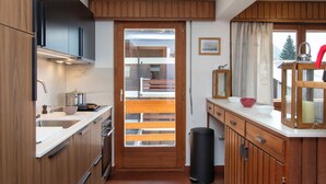 A compact kitchen with wooden cabinets, a sink, and a window overlooking a balcony. - Val Neige 11 by Interhome (Verbier)