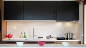 A modern kitchen with dark cabinets, a marble backsplash, a stainless steel sink, and a wooden countertop. - Val Neige 11 by Interhome (Verbier)