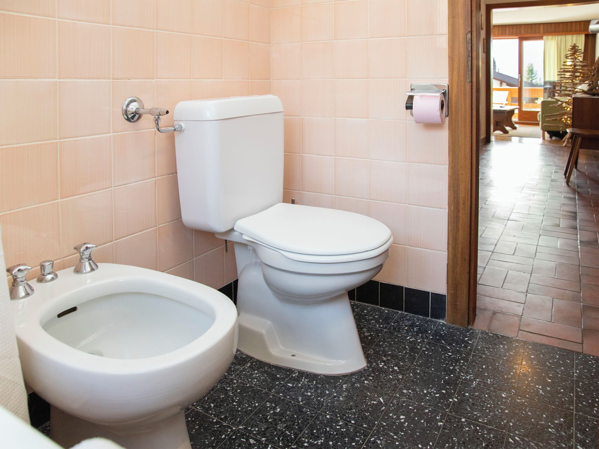 Een badkamer met toilet, bidet en een toiletrolhouder.