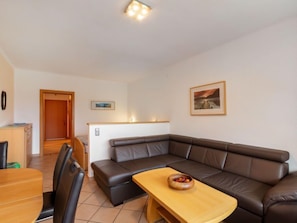 Ein modernes Wohnzimmer mit einem braunen Ledersofa, einem Holztisch und einer Essecke mit Tisch und Stühlen.