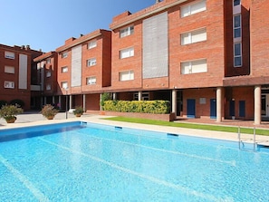 A modern building with a swimming pool, brick exterior, and multiple windows.