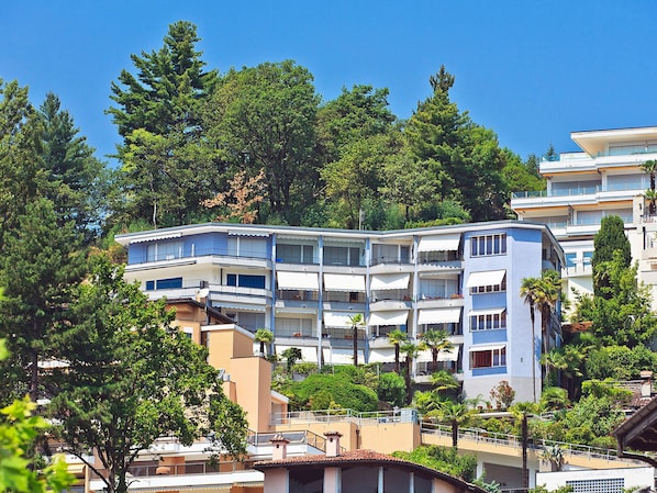 A multi-story hotel with balconies, surrounded by trees and greenery. - Double Room Modern by Interhome (Ascona)