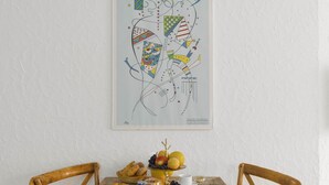 A dining table with breakfast items, a framed abstract art piece, and two wooden chairs. - Double Room Modern by Interhome (Ascona)