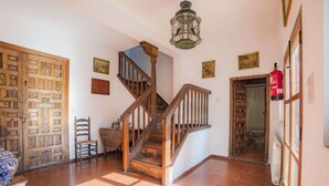Un hall d’entrée spacieux avec un escalier en bois, un revêtement de sol carrelé et une lanterne suspendue.