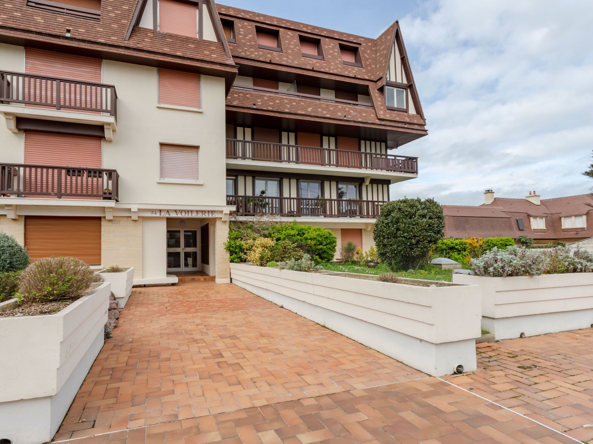 A multi-story residential building with a brick facade, balconies, and a landscaped garden area.