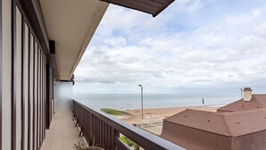 Een balkon met uitzicht op zee, een betegelde vloer en een plant in pot.