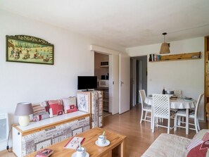 Uma sala de estar aconchegante com um sofá, uma mesa de centro de madeira e um espaço de jantar com mesa e cadeiras.