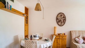 Een eetgedeelte met een ronde tafel, stoelen, een houten kast en een wandklok.