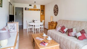 Een gezellige woonkamer met een bank, een salontafel en een eethoek met een tafel en stoelen.