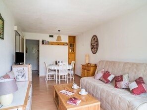 Uma sala de estar acolhedora com um sofá, uma mesa de centro e um espaço de jantar com uma mesa e cadeiras.