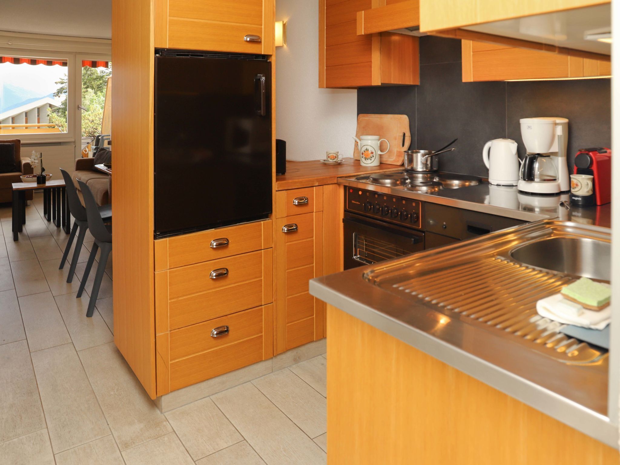 A modern kitchen with wooden cabinets, a black refrigerator, a stove, and a sink.